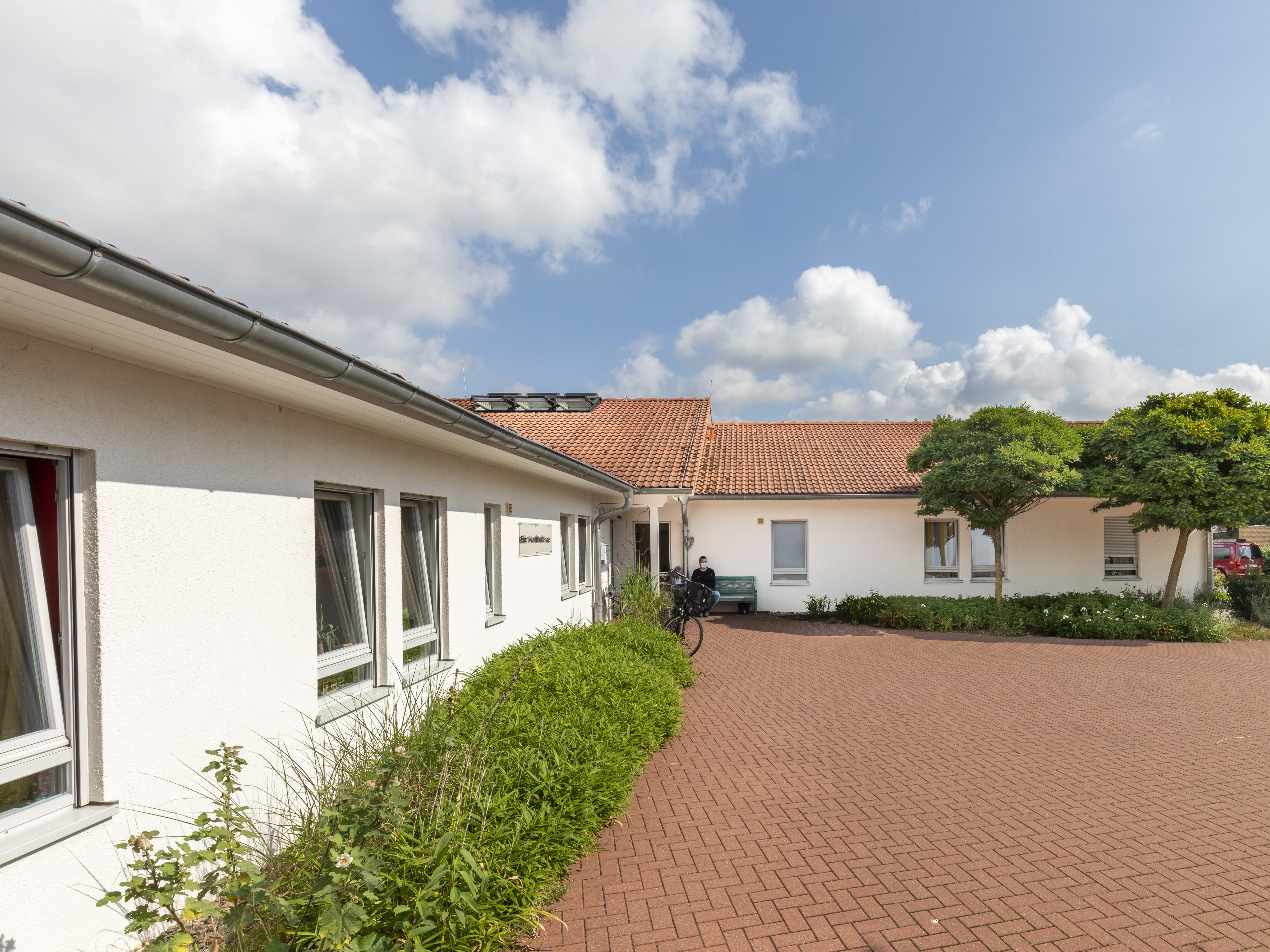 Das flache Gebäude ist weiß. Vor dem Haus ist eine große Auffahrt. 