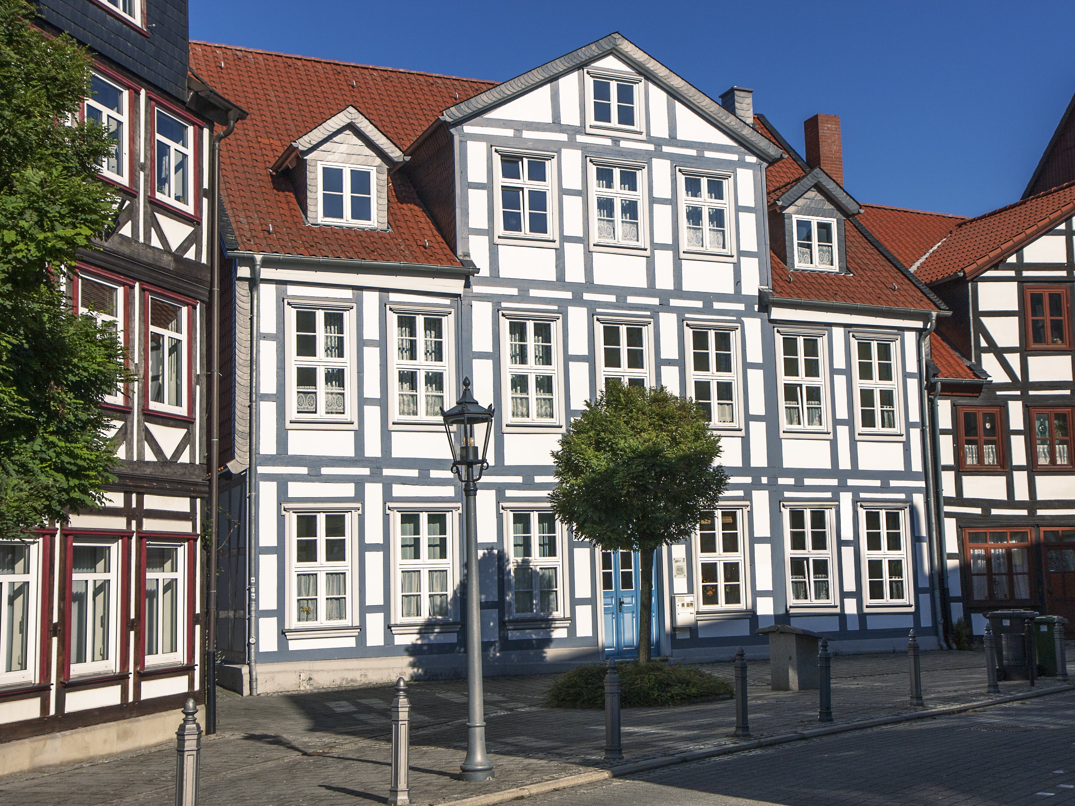 Das Haus im Fachwerkstil hat drei Stockwerke, davon eins im Dachgeschoss. Die sichtbaren Balken des Fachwerks sind blau, der Rest weiß