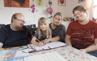 Auf dem Bild sind LHPB-Mitarbeiterin Kristin Kluczyk, Katja Riesebeck, Kevin Uwe Lohse und deren Tochter Linea zu sehen, die gerade zu den Aufgaben in der kommenden Woche beraten.