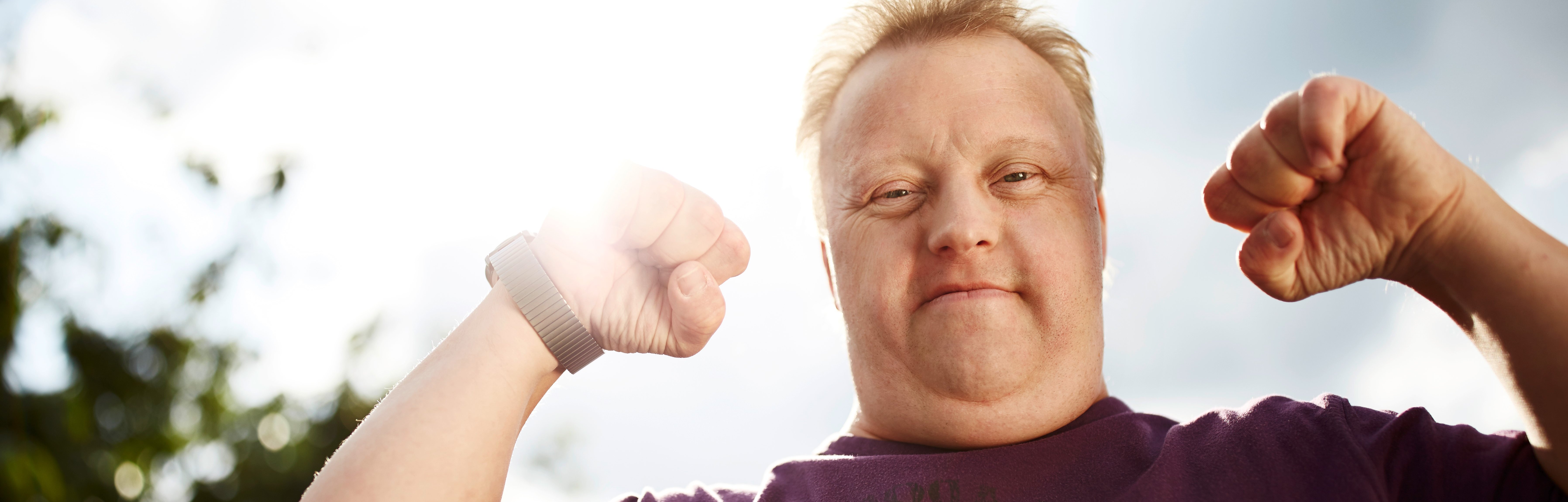 Junger Mann in kraftvoller Pose, als wenn man seine Armmuskeln zeigt.