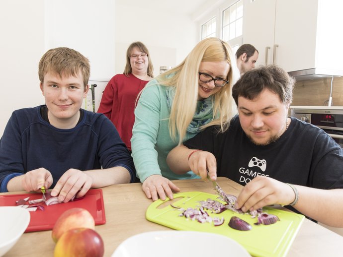 Mehrere Menschen bereiten gemeinsam Essen zu.
