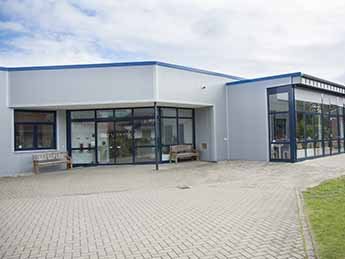 moderne, silberne Gebäudehalle mit bodentiefen Fenstern.